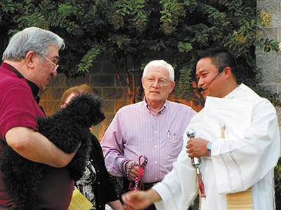 SOUTHAVEN – Father Thi Pham, SCJ, blesses Joe Baker’s poodle at Christ the King Parish on Wednesday, Oct 2. There were also blessings in Olive Branch and Hernando. (Photo by Donna Williams)