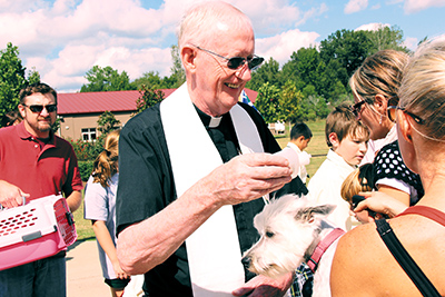 MADISON – Msgr. Michael Flannery, pastor of St. Francis of Assisi Parish, blesses a family pet at St. Anthony School.  The church has a tradition of blessing pets on the feast of St. Francis, who loved animals. (Photo by Jennifer Kelemen)