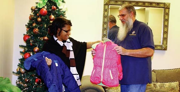 Tony Kumor hands a donated coat to Arteria Puckett, director of the Catholic Charities Battered Womens’ Shelter. 