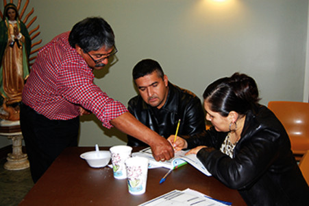 Fausto Ramírez (izq.) le explica a Gerardo y Lupita Fernández como llenar el formulario de control diario durante la clase de planificación natural familiar el 17 de enero en la Catedral de San Pedro. (Foto de Elsa Baughman)