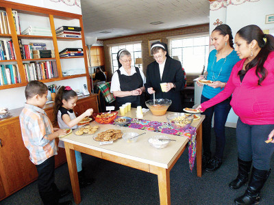(l-r)Sebastian Esparza, Wendy Duron, Sister Kathleen Murphy OSF, Sister Annette Kurey OSF, Nohemi Esparza and Elizabeth Duron make selections from the snack table during open house held Sunday Feb. 8 in Greenwood (Photo and story submitted by Sister Tupy)