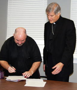 JACKSON – Vicar General Father Kevin Slattery, signs his attestation of the act of installation and profession of faith in the diocesan chancery Monday, March 2.