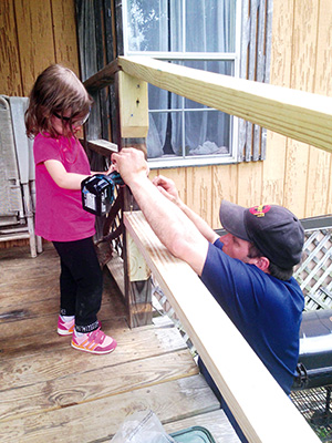 Sadie Dixon helps her father Paul Dixon build a wheelchair ramp. The whole family does summer service.