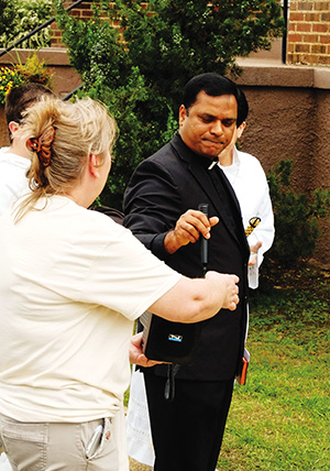 Father Albeenreddy Vatti takes the microphone to bless the new historical marker in front of Fulton Christ the King Church. 