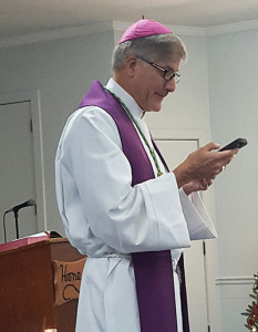 Bishop Kopacz uses his smartphone to read a letter from St. Francis Xavier at the closing Mass for the Lay Ecclesial Ministers. (Photo by Cathy Edwards)