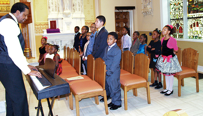 John Alford, director of music for Sister Thea Bowman School, leads the children in song at the Martin Luther King, Jr. Black History Month program.