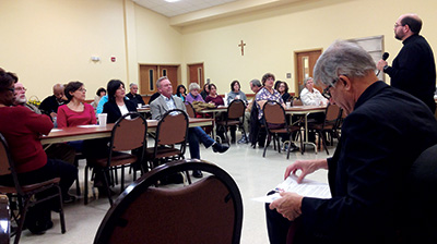 CLARKSDALE – Bishop Joseph Kopacz reviews his notes as Father Rusty Vincent, facilitator for several listening sessions, reviews the instructions to those gathered in Clarksdale. (Photo by Maureen Smith)
