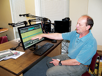 Roger Venable shows a visitor how a computer can play live or pre-recorded shows on his low-power radio station from the studios inside St. Dominic Centre in Jackson. The businessman hopes to find investors to help expand the operation. (Photo by Maureen Smith)