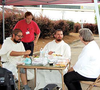 JACKSON – Sister Susan Karina Dickey, OP, (right) talks with the friars while they eat a light lunch before departing to Madison accompanied by four parishioners from Flowood St. Paul.