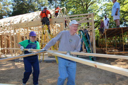 Volunteers Polly Hammett of St. Francis of Assisi and Msgr. Elvin Sunds of St. Therese help position the trusses for the 2016 Catholic Build House on Greenview Drive in Jackson. (Photos by Peggy Hampton)
