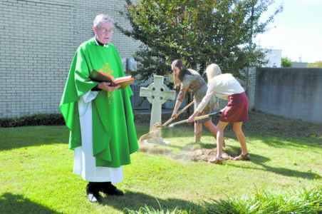 VICKSBURG – Father Tom Lalor, pastor of St. Paul Parish, reads a blessing while CYO members from Vicksburg bury a time capsule on Sunday, Oct. 23, as part of the parish 175th anniversary celebration. The time capsule will be dug up at the church's 200th anniversary in the year 2041.