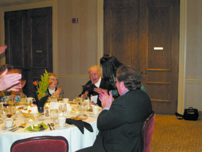 Jack Bellan, at right, surrounded by friends and family, accepts the Good Steward Award from Rebecca Harris, executive director of the Catholic Foundation. (Photo by Maureen Smith)