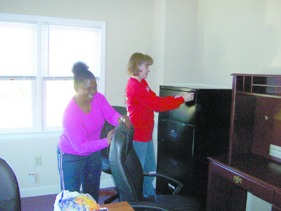 Amy Turner, director of Childrens' Services, and Rena' Tanner, administrative assistant in Therapeutic Foster Care, set up their new offices at Catholic Charities' new headquarters on River Place in Jackson. (Photo by Elsa Baughman)