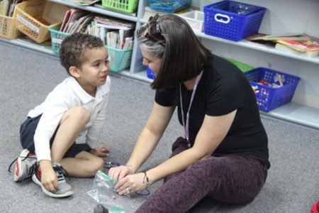 COLUMBUS – Annunciation School kindergarten teacher, Heather Ford, (above photo) helps student, Ashley Studdard, make a turkey bracelet as a way to teach him about the meaning of the Thanksgiving celebration.