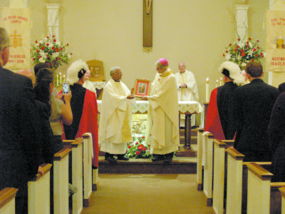 Father Aroika Savio, left, presents a framed photo to Bishop Joseph Kopacz during the 75th anniversary celebration at St. Peter Parish.