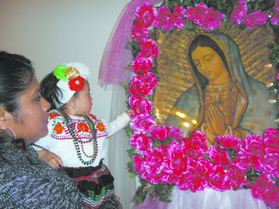 A baby reaches for the image of Our Lady of Guadalupe during the celebration at St. Christopher in Pontotoc. 
