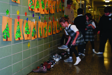 NATCHEZ – Cathedral School elementary students had a visit from St. Nicholas on his feast day of Dec. 6. Above, surprised first grader Aven Adcock collects treats from her shoe in the hallway. (Photo courtesy of Cara Serio) 