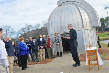 MADISON –  Bishop Joseph Kopacz blesses a new telescope at the Hulett observatory at St. Joseph High School on Friday, Jan. 27. As part of the dedication, Nobel Prize winning astrophysicist Alex Filippenko visited the school, speaking to students, parents and even visiting Millsaps College while he was in town. In right photo, Phillip Smith listens to Filippenko speak at one of the public events. The scientist spoke about his love for science and encouraged students to explore and make new discoveries. He joked with the bishop that he had never been to a telescope blessing before.  (Photos by Dave Vowell of Vowell photography)