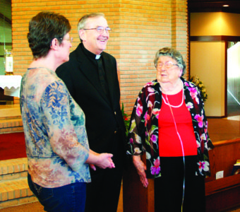 At left, Julie Harkins, parish secretary, Father Thomas McGing, pastor, and Ivy Callegan, founding member and donor, talk about the new window.